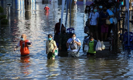 People wade through a flooded street in Chaiyaphum province, Thailand