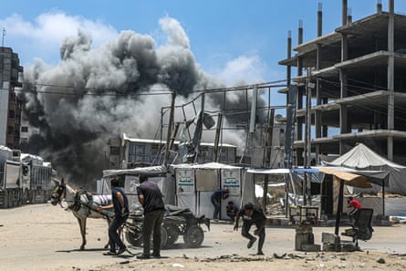 People run for cover as an Israeli airstrike lands on the west side of Gaza City