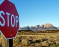 A stop sign stands before grassland, with Grand Teton national park's jagged mountains beyond