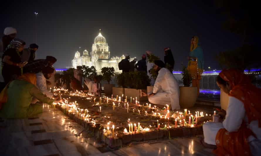 Devotees light candles at sunset at the illuminated Gurudwara Bangla Sahib Temple in New Delhi.