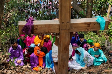 Image 28: People in colourful dress pray in front of a cross