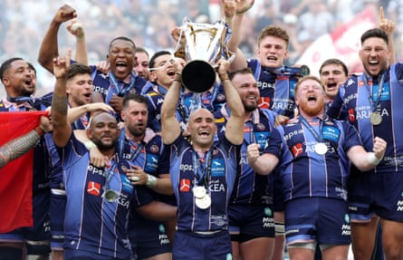 Maxime Lucu of Union Bordeaux Begles lifts the Champions Cup Trophy as the team celebrates