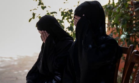Two Afghan sisters who have been forced into marriages sit and cover their faces with their hands