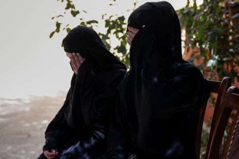 Two Afghan sisters who have been forced into marriages sit and cover their faces with their hands