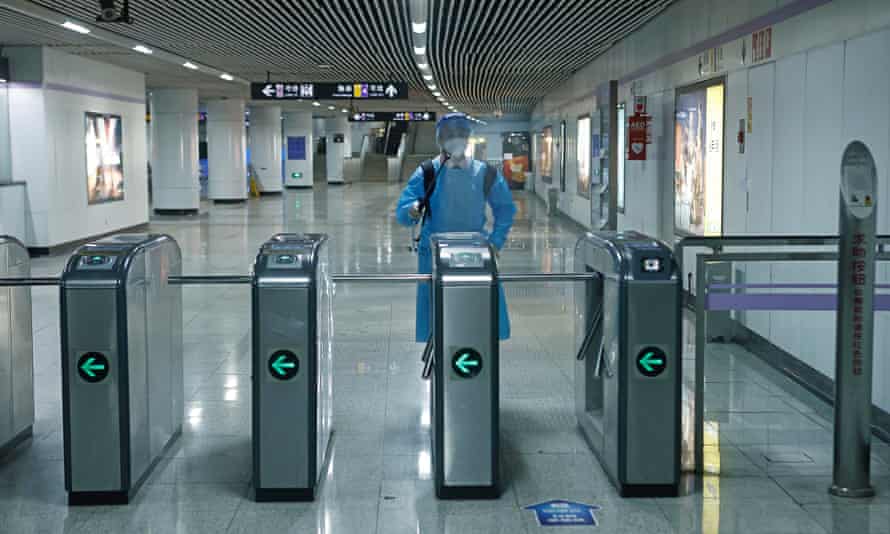 A rail staff member in a protective suit sprays disinfectant at a subway station in Shanghai, China, as four rail lines resumed service on Sunday