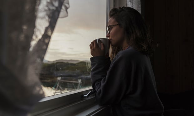 Young woman looking out of window, drinking tea mental health