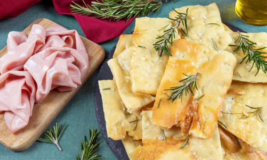 White Roman focaccia with rosemary and coarse salt accompanied with slices of mortadella.