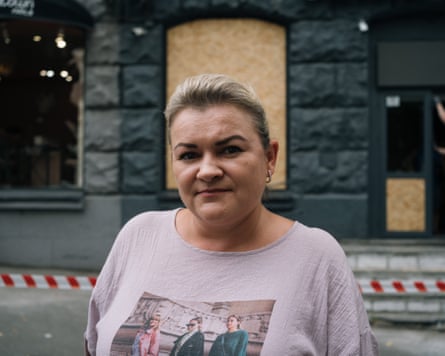 Nataliya Serhiyivna, wearing a T-shirt, poses for a photograph outside a boarded-up building