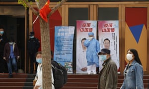 A medical worker adjusts her mask near propaganda boards showing famed Chinese medical expert Zhong Nanshan and the words “Vaccine China Made” outside vaccination center in Beijing Friday, April 9, 2021.