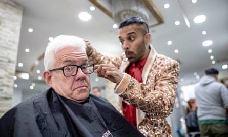 Oscar Castellino pretends to cut the hair of Ian McMillan as he sits in a barber’s chair