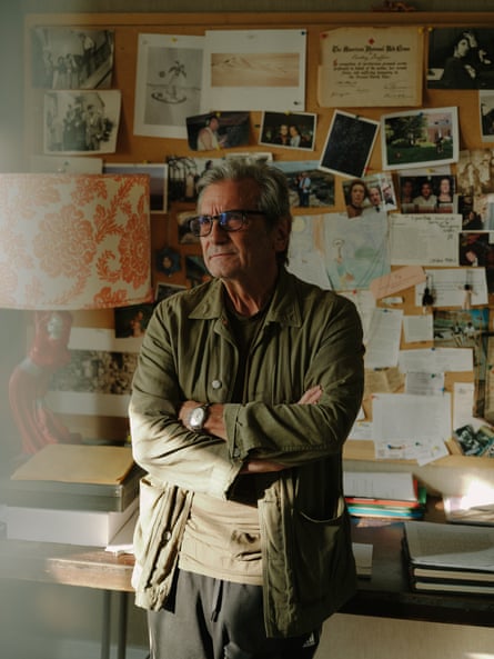 Actor Griffin Dunne, leaning against a desk, a pinboard of dociments and photographs behind him