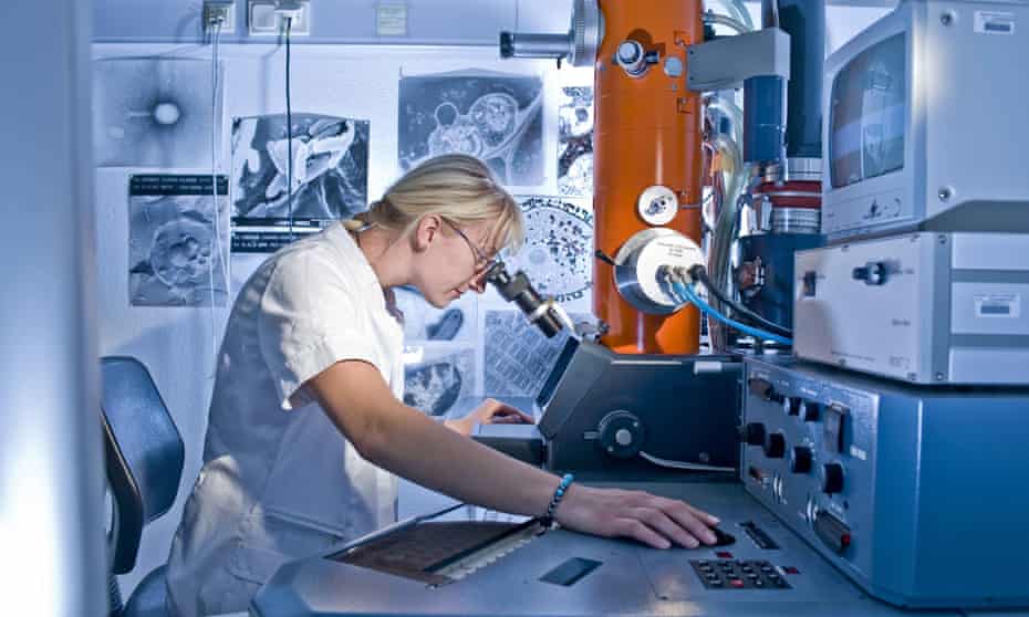 Female laboratory technician working on an electron microscope
