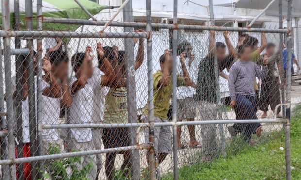 Asylum seekers stand behind a fence in Oscar compound at the Manus Island detention centre