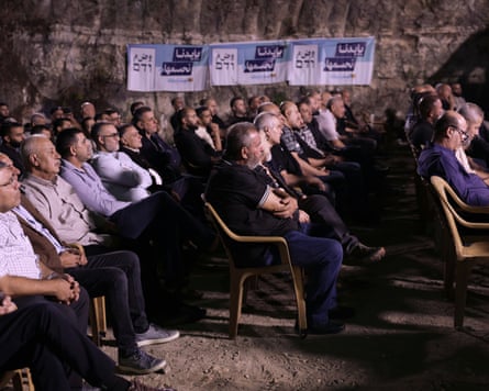 Rows of people sitting, listening to an out-of-shot speaker.