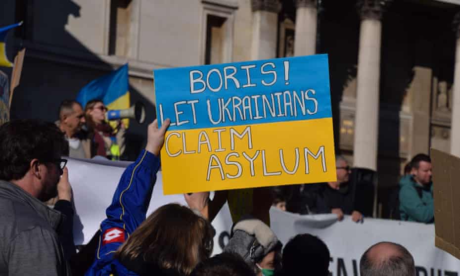 A protester holds a placard calling on Boris Johnson to let Ukrainians claim asylum.