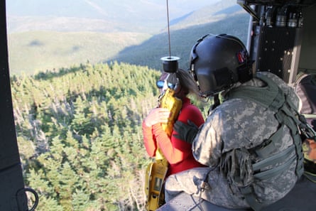 A woman on a winch is helped into a helicopter