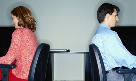 woman and man sitting at desks with backs to each other