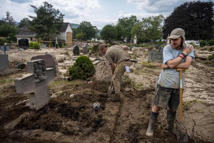 Benjamin Monschau, right, and his assistant Johannes Ehmer remove hard clay from their grandfather's grave