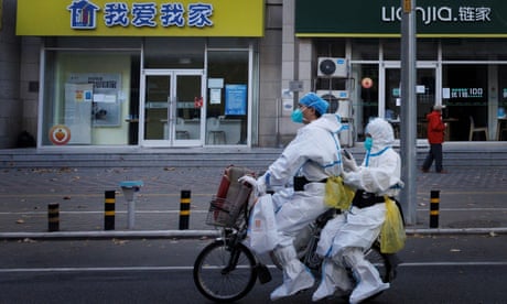Pandemic prevention workers in protective suits ride an electric bike in Beijing