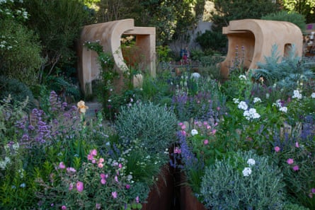 A garden with pink, purple and white flowers with cabins in the background