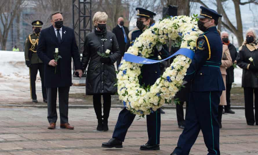Health workers carry a wreath as Quebec Premier Francois Legault, left, and his wife Isabelle Brais look on during a ceremony for the victims of COVID-19.