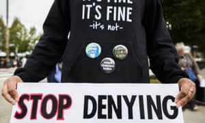 A man carrying a sign saying 'Stop denying'