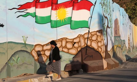 An Iraqi Kurdish woman walks past a mural in Arbil, the capital of the autonomous Kurdish region of northern Iraq