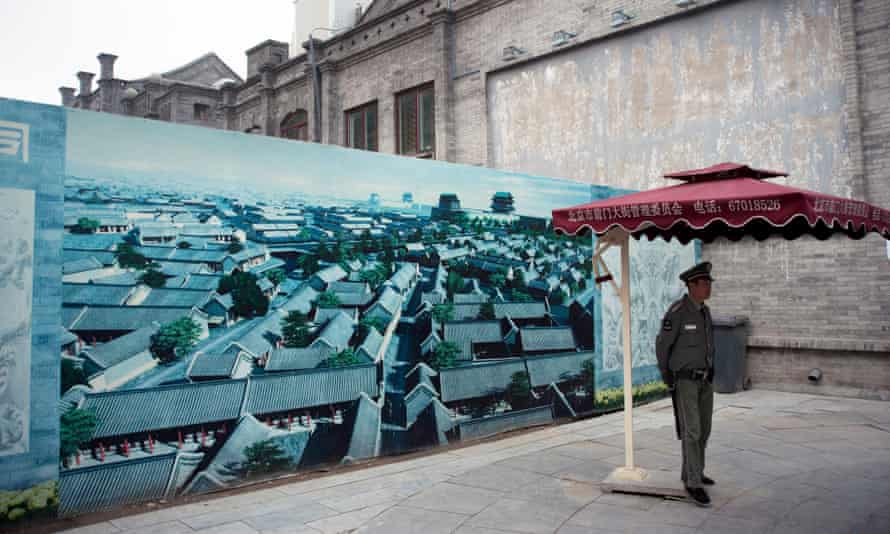 A guard stands by the illustration of a project to renovate Beijing’s Qianmen street, in 2012.