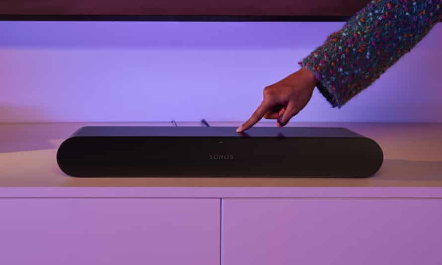 A hand touching a button on the top of the Sonos Ray soundbar.