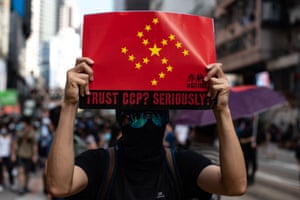 An activist displays a poster with the stars of the Chinese flag arranged in a swastika symbol