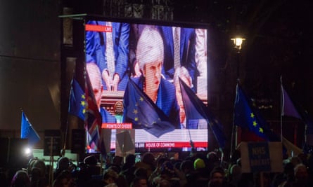 Protesters’ flags flutter as video of Theresa May is shown outside the Houses of Parliament, after she was defeated in the vote on the EU withdrawal agreement.