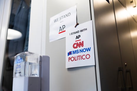Printed signs of support tacked to a gray wall beside a water cooler