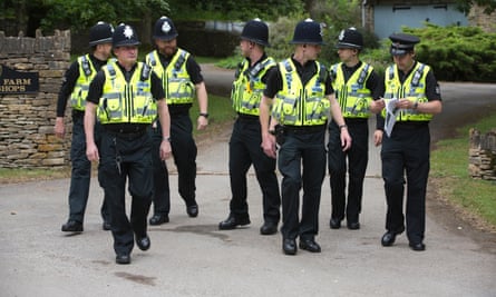 Seven police officers with helmets, in short-sleeved shirts and protective vests, on the pavement