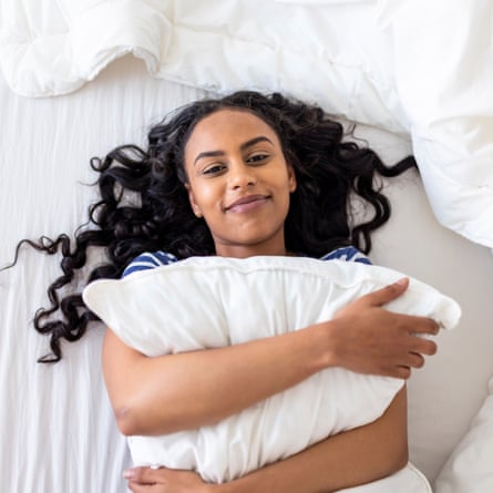 Happy woman embracing a pillow on bed at home