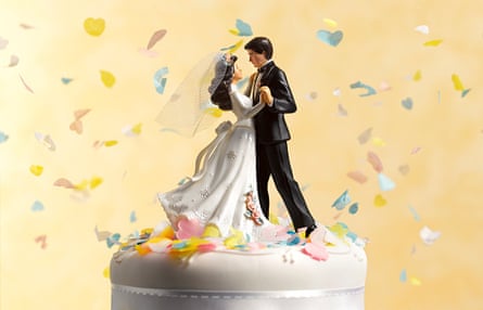 Dancing figurines of a bride and groom on top of a wedding cake, with confetti fluttering around them
