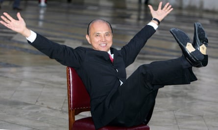 Jimmy Choo sits on a chair his arms out and his legs stretched out