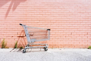 Empty shopping cart against a pink brick wall
