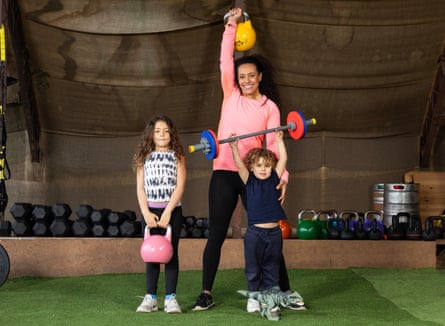 Evelyn Stevenson holding a kettlebell above her head, flanked by Madison holding a kettlebell with both hands and Beau holding up a child’s barbell.