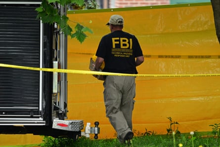 A man with a shirt saying "FBI" carries a box