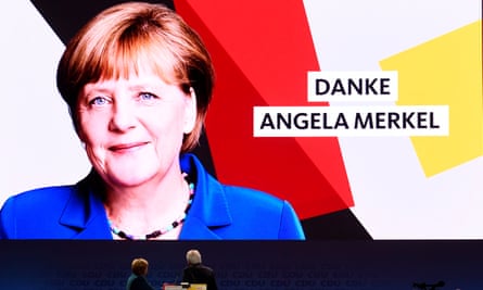 Merkel looks up at a vast sign thanking her for her leadership.