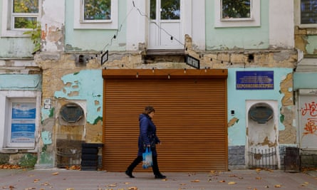 A woman walks past damaged buildings along a street in Kherson.