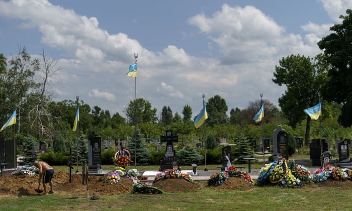 The graves of recently killed Ukrainian soldiers line a cemetery as a gravedigger covers the casket of Serhiy Marchenko following his burial service in Pokrovsk, Donetsk region, eastern Ukraine, Thursday, Aug. 4, 2022. Marchenko, 26, was killed in battle July 28 with Russian forces in the Donetsk region. (AP Photo/David Goldman)