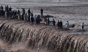 Pakistanis cross a flooded street following heavy rain on the outskirts of Peshawar on 4 April 2016.