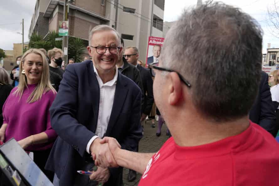 Anthony Albanese shakes hands with a voter as he and his partner Jodie Haydon arrive to vote in Marrickville