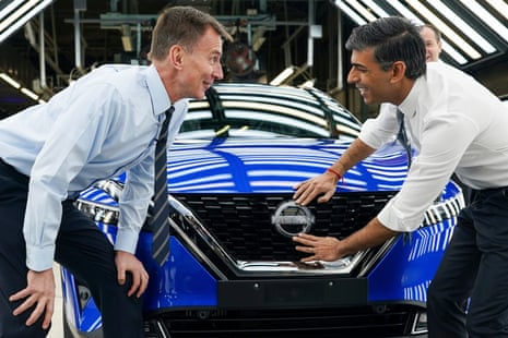 Rishi Sunak attaching a Nissan badge at the Nissan plant in Sunderland, with Jeremy Hunt alongside him.