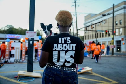 The Long Wave: Unearthing the real story of Black voters at the US election A woman wearing an ‘It’s about US’ T-shirt holds her Maltese rat terrier, Cleopatra, on a busy street