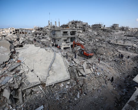 In Gaza City, an excavator and workers search rubble of buildings destroyed in Israeli attacks