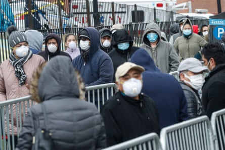 People wear face masks as they wait in line for coronavirus testing at Elmhurst hospital on 25 March.