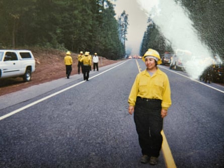 A woman in a yellow top and black pants standing on a road.