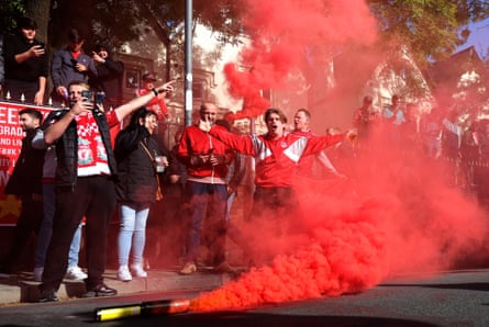 Red smoke fills the air in front of Liverpool supporters.